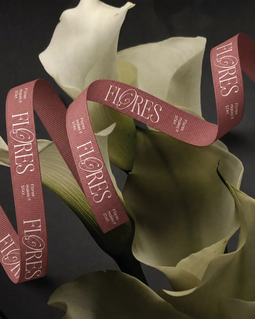 A dusty-rose grosgrain ribbon printed with FLORES and Flores makes it stay, curling around calla lilies